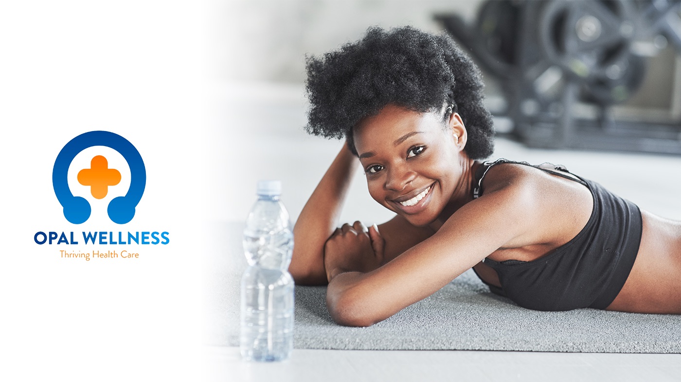 A woman resting on a gym mat beside the Opal Wellness logo