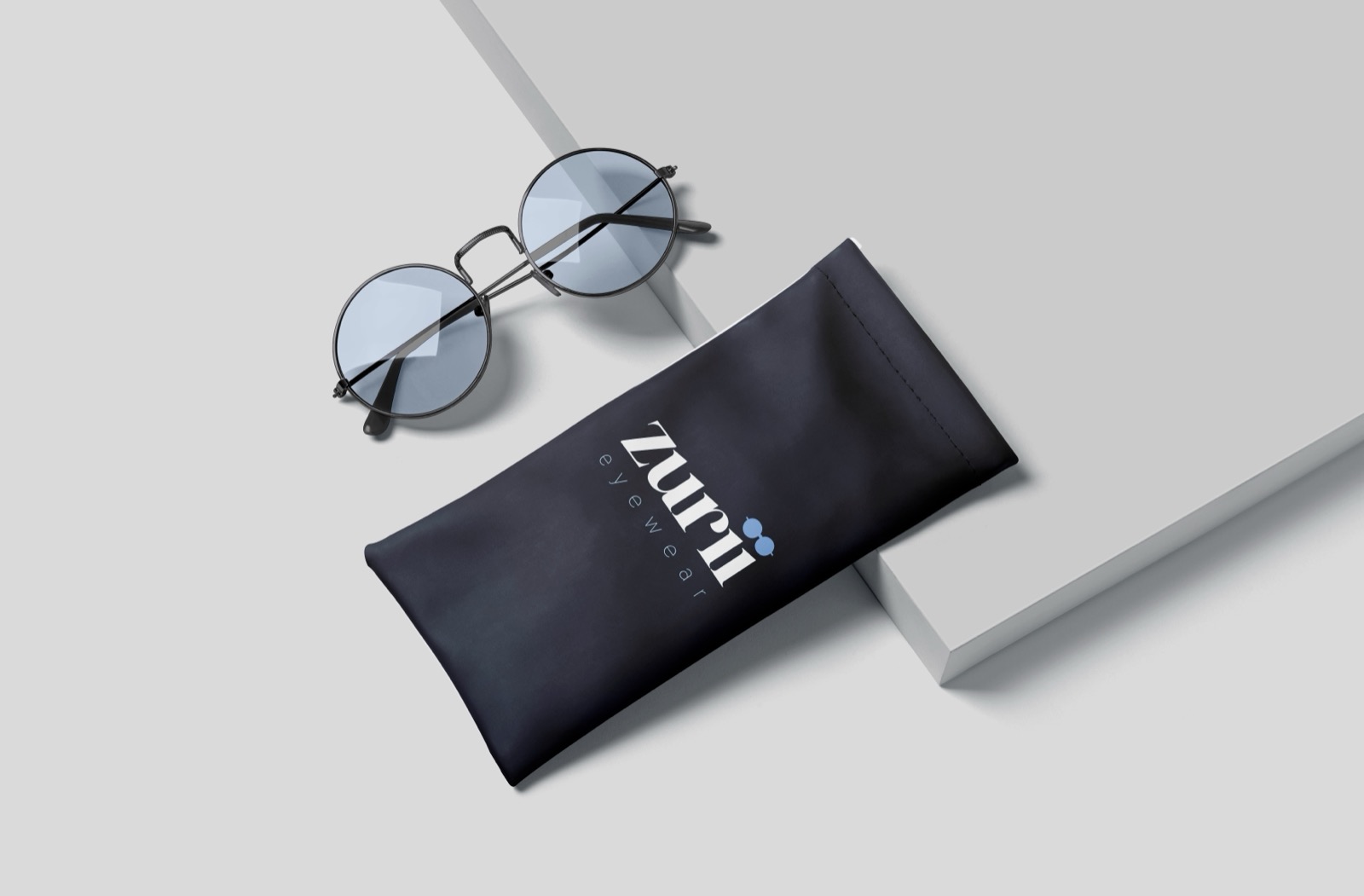 Round Zurii Eyewear glasses beside a navy branded pouch